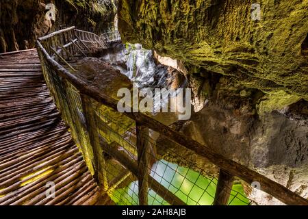 Wide angle view of a wooden catwalk leading into a gorge with green water on its bottom Stock Photo