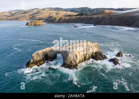The Pacific Ocean washes against a sea stack off the northern California Sonoma coast. This region is often covered by a thick marine layer of mist. Stock Photo