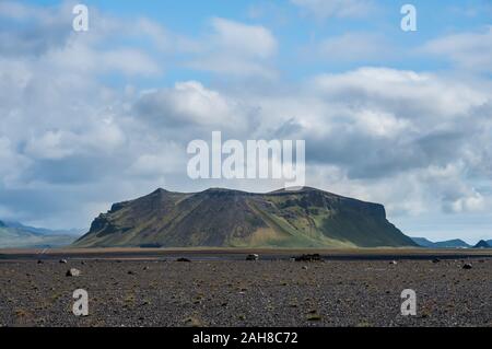 Symmetrical wide angle view of a southern icelandic landscape, with a desert and a distant mountain, under a blue sky with puffy clouds Stock Photo