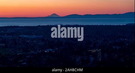 Saanich, Oak Bay, and Victoria in British Columbia, Canada, seen from Mount Douglas (Pkols) at dawn with Mount Rainier on the horizon. Stock Photo