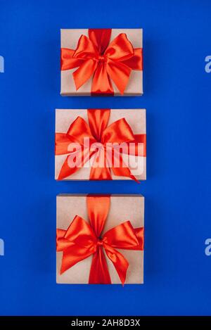 Three cardboard gift boxes with bows on blue background. Stock Photo