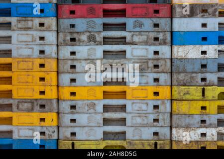 stacks or piles of packaging or storage crates made from plastic multi-coloured for storing the fishermans catch. Stock Photo