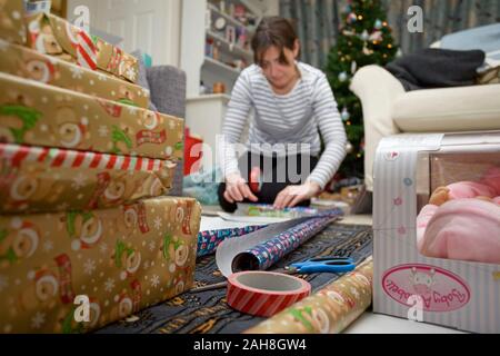 Young woman wrapping Christmas presents on the floor Stock Photo