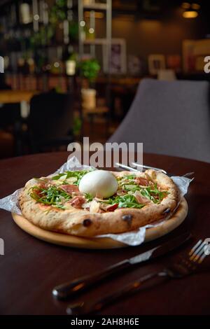 Food concept. Fresh original Italian Pizza with burrata, prosciutto and arugula. Ready to eat. Stock Photo