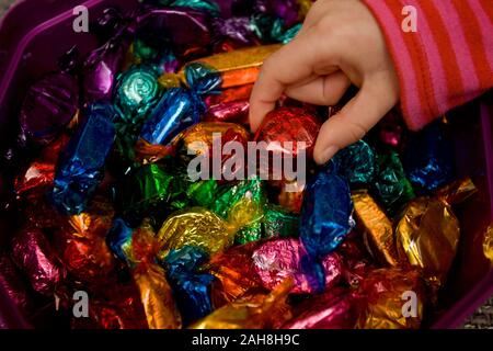 Childs hand picking out favourite quality street chocolate Stock Photo