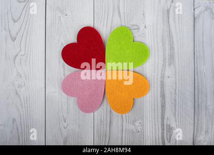 four coloured hearts on a grey and white wooden background. Concept of St. Valentine's Day Stock Photo
