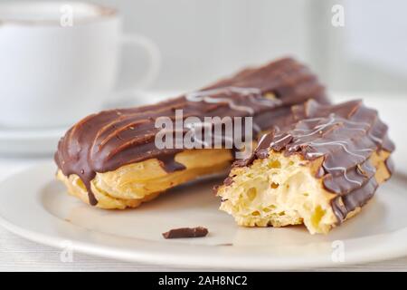 Whole and bitten of eclair on light background Stock Photo