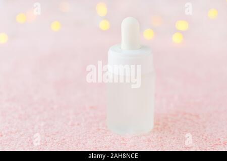 natural face serum in a glass bottle on pink background with bokeh, soft focus Stock Photo