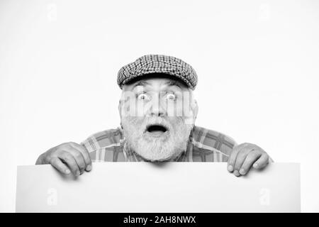Elderly person. Announcement concept. Event announcement. Senior bearded emotional man peek out of banner place announcement. Pensioner grandfather in vintage hat poster information copy space. Stock Photo