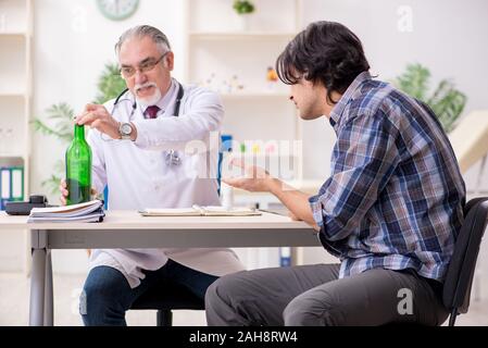 The young male alcoholic visiting old doctor Stock Photo