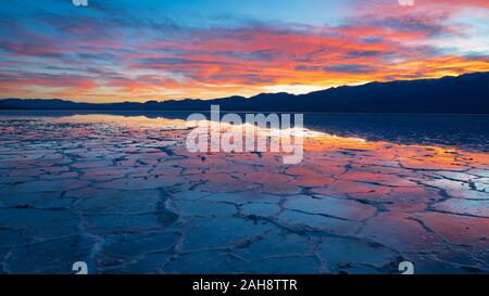 Colourful sunset over a flooded Badwater Basin in the Death Valley National Park with reflections of mountains in water in California on 14 Dec 2019 Stock Photo