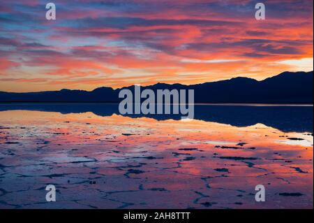 Colourful sunset over a flooded Badwater Basin in the Death Valley National Park with reflections of mountains in water in California on 14 Dec 2019 Stock Photo