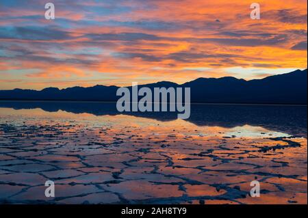 Colourful sunset over a flooded Badwater Basin in the Death Valley National Park with reflections of mountains in water in California on 15 Dec 2019 Stock Photo