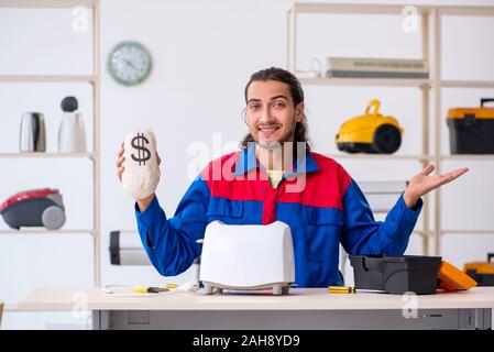 The young male contractor repairing toaster at workshop Stock Photo