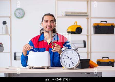 The young male contractor repairing toaster at workshop Stock Photo