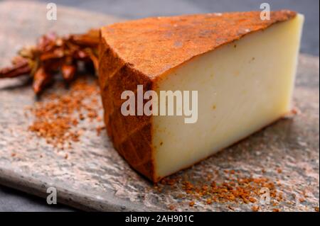 Cheese collection, piece of Spanish manchego cheese made from cow milk with red paprika close up Stock Photo