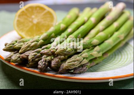 Bunch of fresh green raw organic asparagus with lemon ready to cook close up Stock Photo