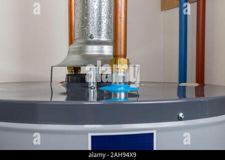 Closeup of natural gas or propane hot water heater flue exhaust vent and copper plumbing pipe Stock Photo