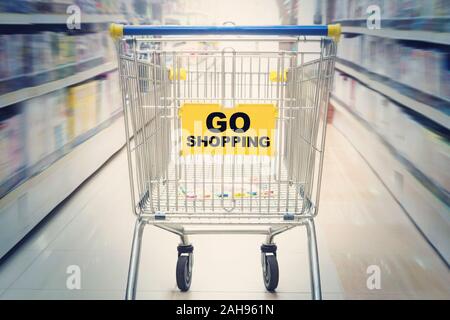 move in the supermarket with shopping cart. Go shopping inscription on the cart in the shopping Mall. concept of shopping in the market. Stock Photo