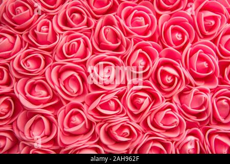 a lot of roses in the background. Texture of bright red artificial roses. Stock Photo