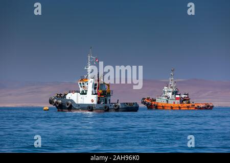 Two fishing boats stand in the sea against the backdrop of desert mountains in the ocean. Fishing boats at sea. Stock Photo