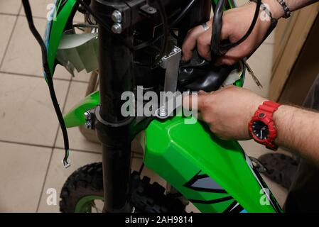 The process of connecting electrical wires in the assembly of a new motorcycle in operation. The process of assembling a new motorcycle. Stock Photo