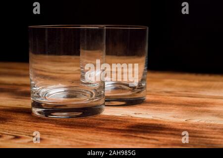 Empty glasses for whiskey on a wooden table. Two glasses for whiskey stand on a wooden table. Stock Photo