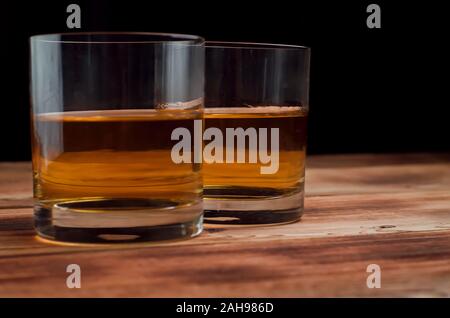 Two glasses with whiskey stand on a wooden table. Glasses with whiskey without ice. Stock Photo