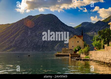 Old stone house in Kotor Bay or Boka Kotorska and surrounding mountains with crystal clear water in the Balkans, Montenegro on the Adriatic Sea