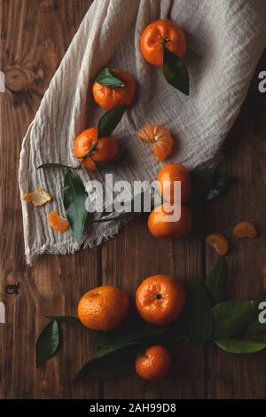 Flat lay with tangerines with leaflets and textile on a wooden background. Stock Photo