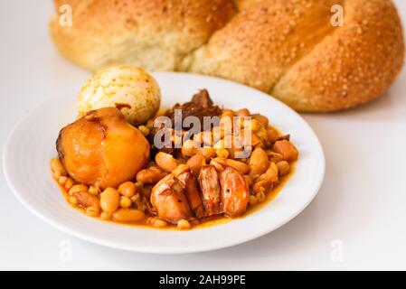 Challah Shabbat bread and hamin or cholent in hebrew - Sabbath traditional food on white table in the kitchen.Top view. Stock Photo