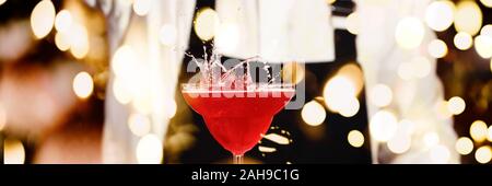 Barman in making cocktail at a nightclub. Nightlife concept. No face. Pouring into glass.. Horizontal, banner format with festive bokeh lights Stock Photo