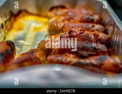 Selective focus and close up of pigs in blankets, sausage wrapped in bacon, in an aluminium foil tray Stock Photo