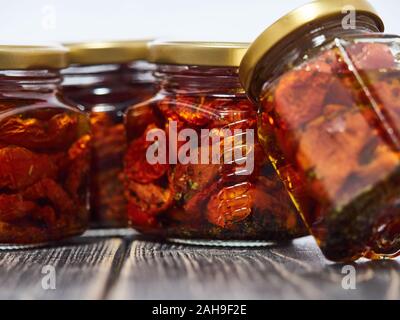 Home-made canned red dried cherry tomatoes are packed in small glass jars. Stock Photo