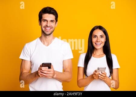 Photo of two people addicted to reposts and subscribers can't live without telephones, wear casual clothes isolated yellow color background Stock Photo