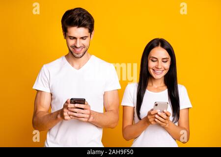 Photo of two people don't mind each other look telephones checking, instagram followers wear casual clothes isolated yellow color background Stock Photo