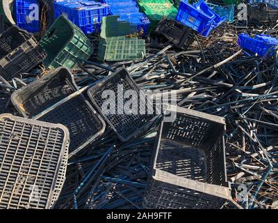Empty Plastic Crates Boxes and plastic pipes Piled Up At The Dump. Stock Photo
