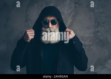 Close-up half-faced portrait of nice attractive focused bearded gray-haired man wearing putting on modern look hood jacket coat isolated over concrete Stock Photo