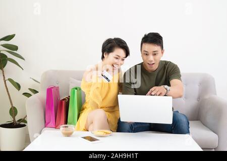Young Asian Couple Making Online Purchases On Laptop At Home Stock Photo