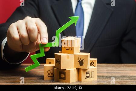 Businessman holding a green arrow up over boxes. Tactics and strategy, marketing. Value added goods. Boost sales rate. Increasing production of goods, Stock Photo