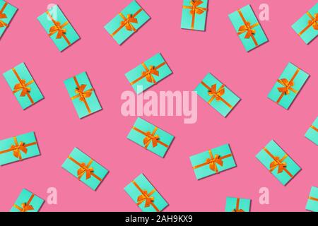 Orange bow on a mint boxes located on pink background. Stock Photo