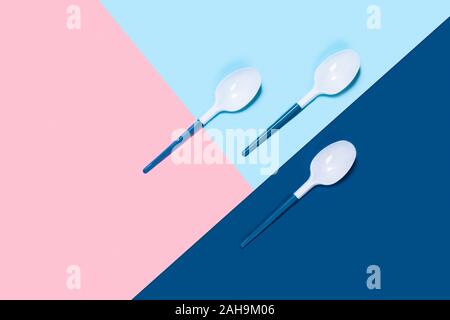 Dangerous three plastic spoons. Tricolor background. Flat lay, top view, copy space. Stock Photo