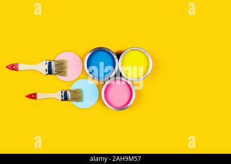 Renovation picture. Yellow background with three color pain cans and two brushes. Flat lay, top view, copy space. Stock Photo