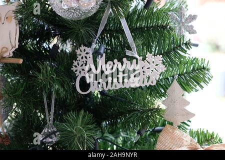 December 2019 - White and silver Christmas decorations hang on a traditional, artificial green Christmas tree Stock Photo