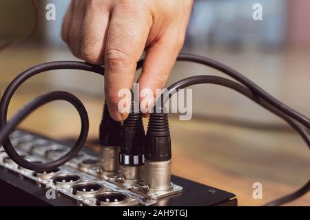 Hand push xlr connector to the analog mixer before recording Stock Photo