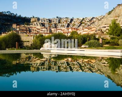 Reflections in the water of an outdoor swimming pool of the houses in the holiday village of Portopiccolo during a sunny day. Example of environmental Stock Photo