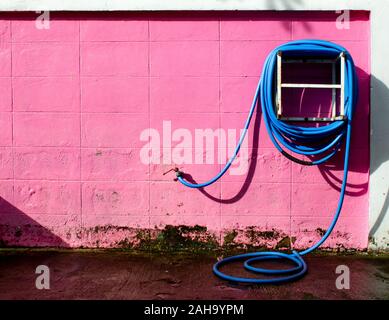 Water hose winder wall pink. After the analysis is completed Stock Photo