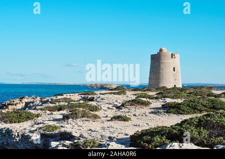 a view of the medieval tower Torre de Ses Portes in Ibiza Island, Spain, and the neighboring Formentera Island in the background Stock Photo
