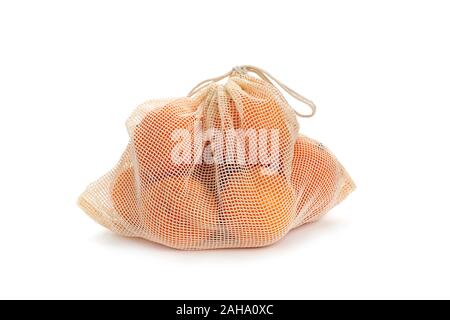 some oranges in a textile reusable mesh bag used to buy groceries in bulk, as a measure to reduce plastic pollution, on a white background Stock Photo