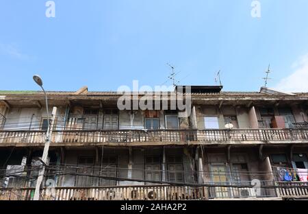 Outside view of vintage building with blue sky background, the building has peeled wall and wooden doors with long balcony Stock Photo